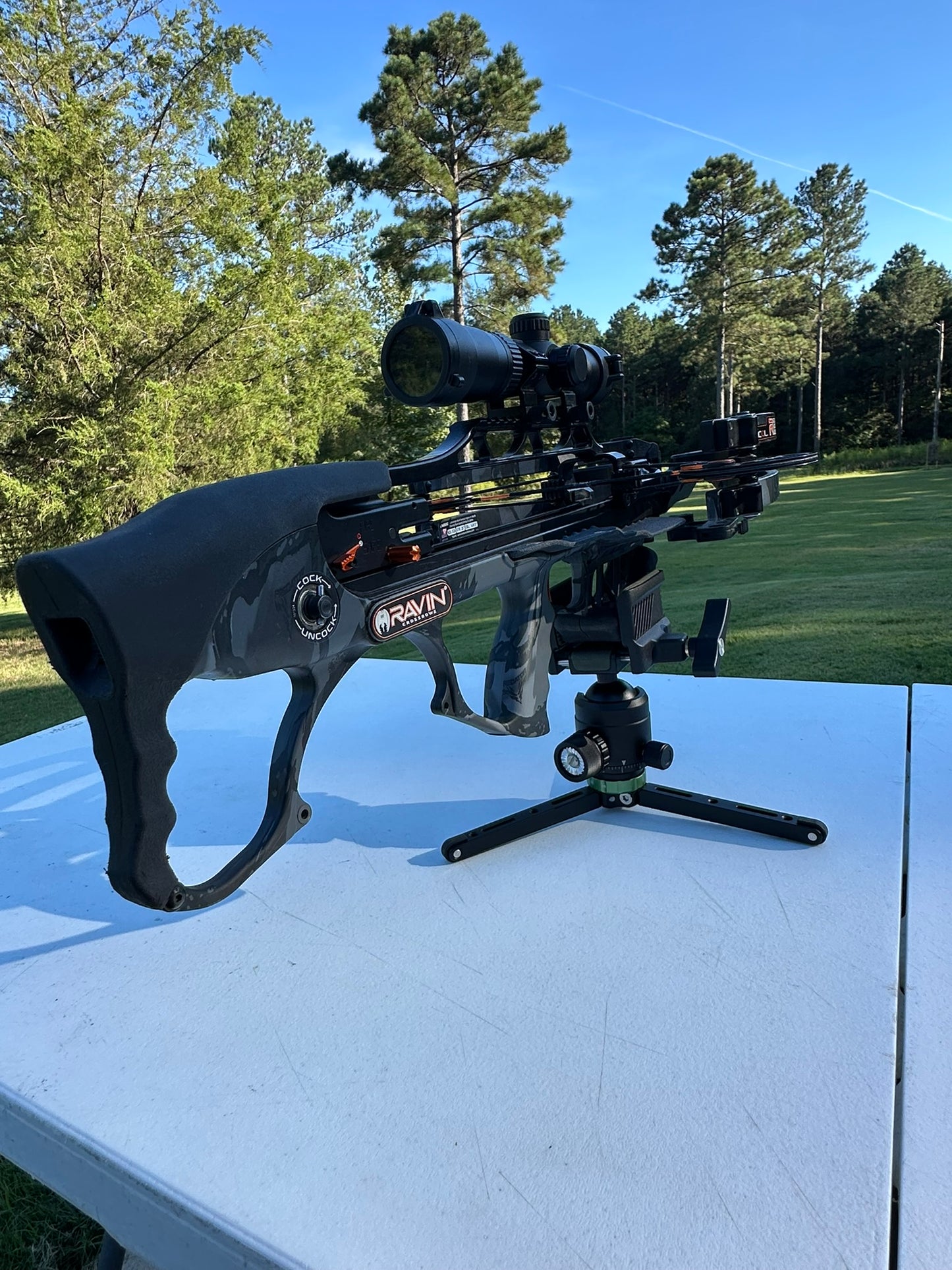 Crossbow with scope on a white surface outdoors